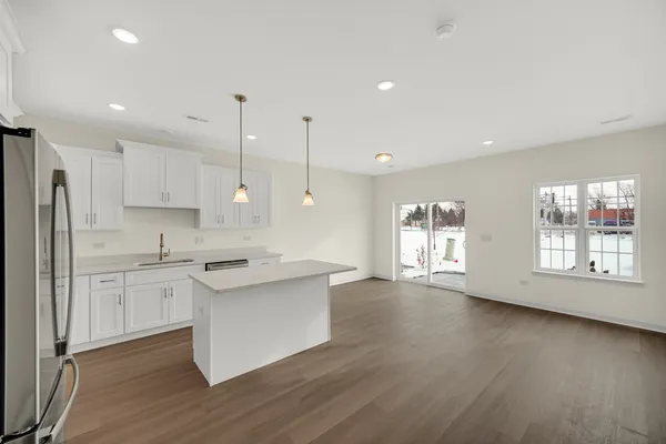 a kitchen with stainless steel appliances granite countertop a stove a sink a refrigerator white cabinets and wooden floor next to a window