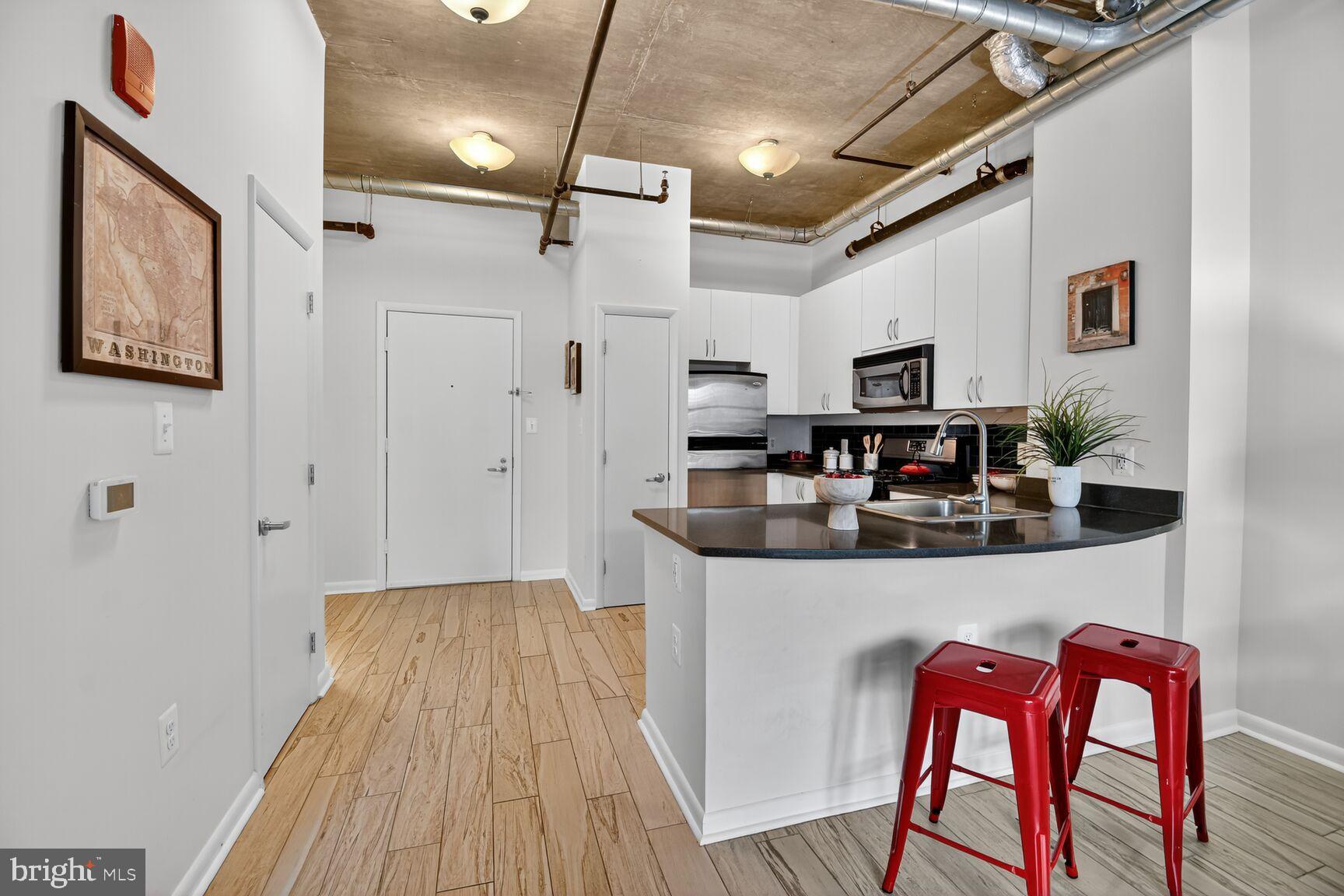 1300 N Street Northwest, Unit 214 Washington, DC 20005 - Photo 6 of 41 a kitchen with stainless steel appliances granite countertop a white cabinets and wooden floor