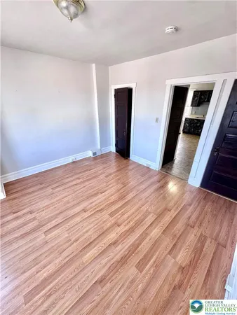 a view of an empty room with wooden floor and entryway