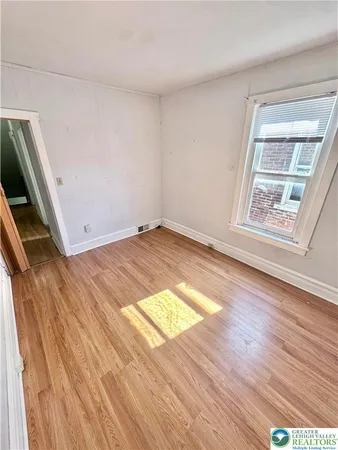 a view of an empty room and wooden floor and a window