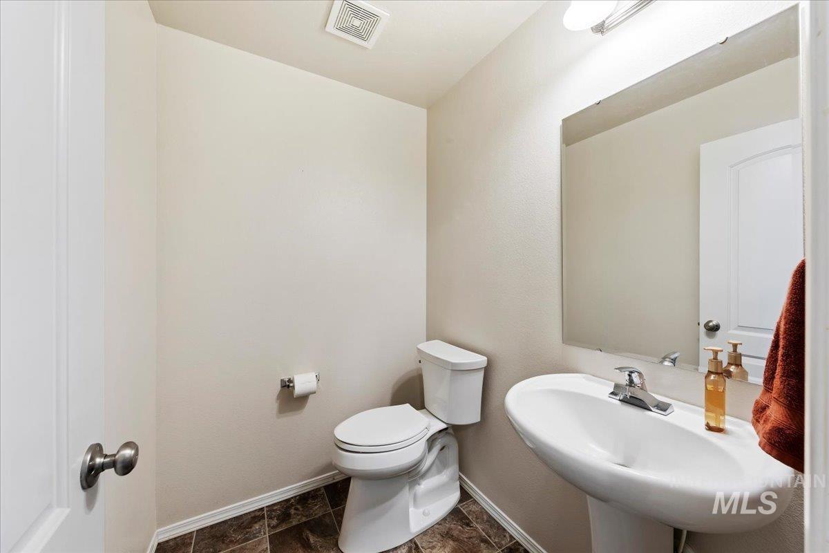 1555 Condor Drive Middleton, ID 83644 - Photo 20 of 50 Pedestal sink with chrome faucet, large vanity mirror, white toilet, and patterned tile flooring