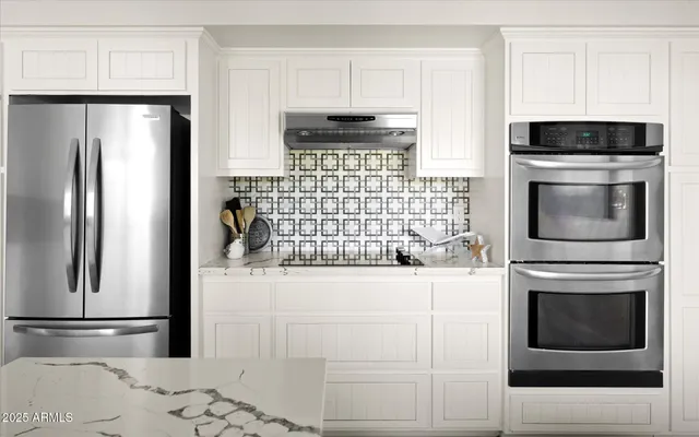 a kitchen with granite countertop white cabinets and stainless steel appliances