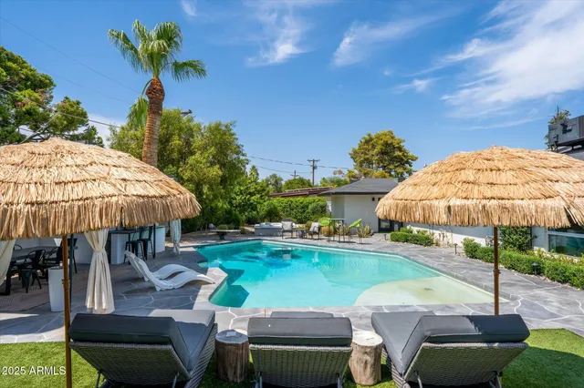 a view of a patio with chairs and table under an umbrella with swimming pool