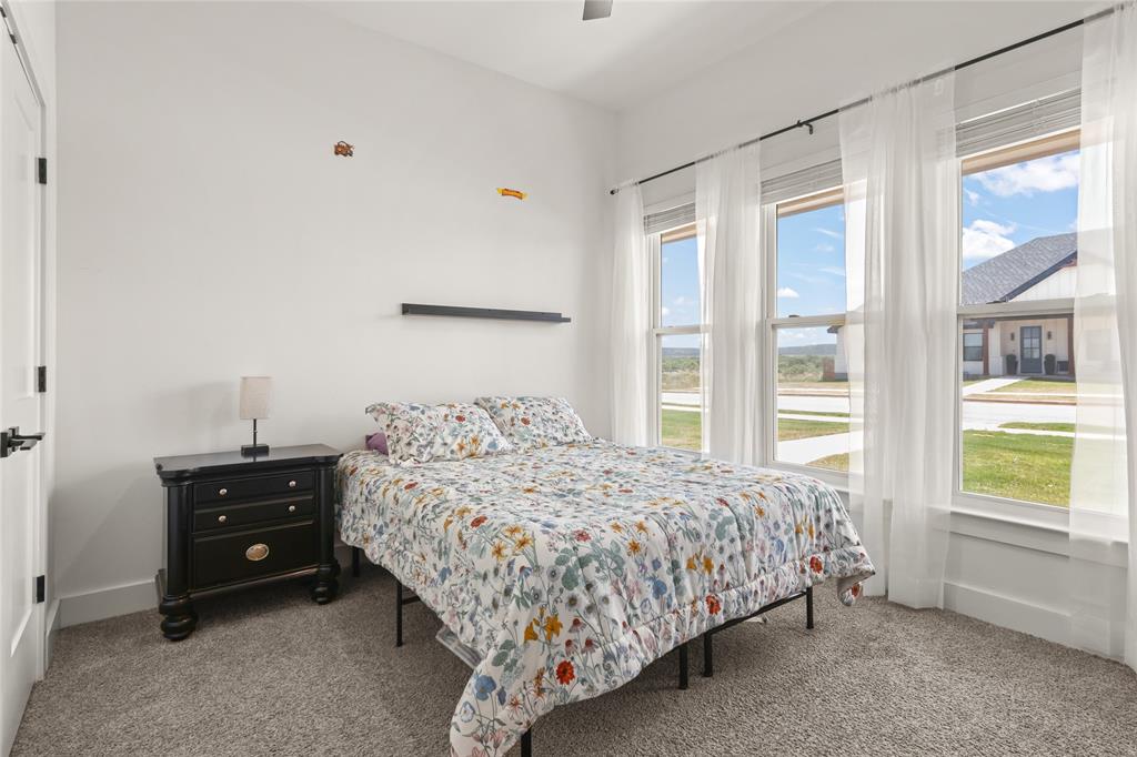 120 Long Ranger Road Abilene, TX 79602 - Photo 17 of 23 Bright room featuring three tall windows with white trim, gray carpet flooring, and a white door with black hardware