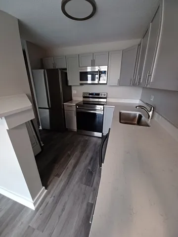 a kitchen with granite countertop a refrigerator a sink a stove and microwave