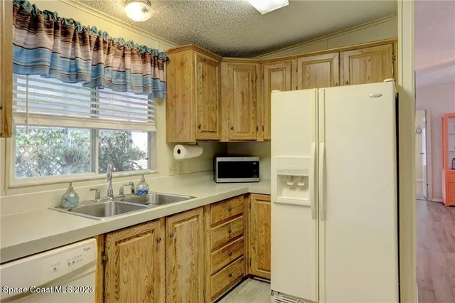 a kitchen with stainless steel appliances a sink a refrigerator and a window