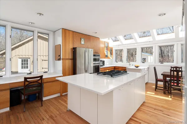 a kitchen with stainless steel appliances a stove top oven a refrigerator a dining table and chairs with wooden floor