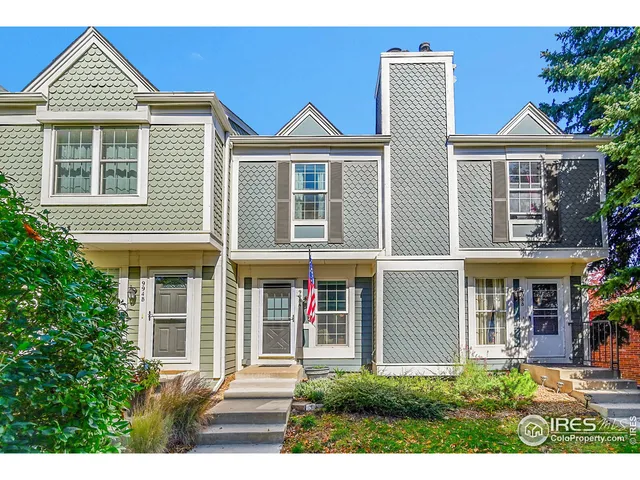 a view of a brick house with large windows and a table and chairs