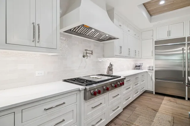 a large white kitchen with lots of counter space a sink appliances and a counter top space
