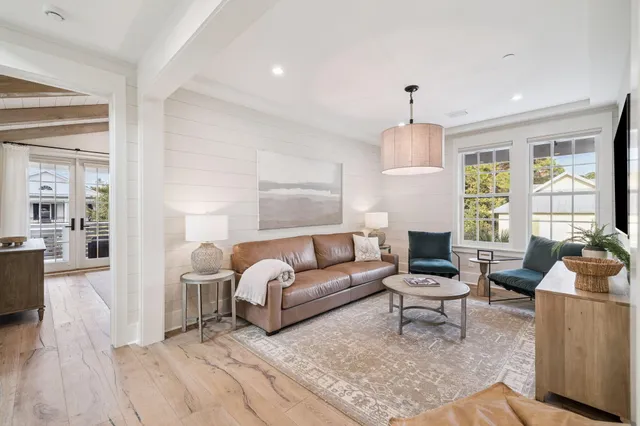 a view of a patio with couches chairs potted plants and wooden floor