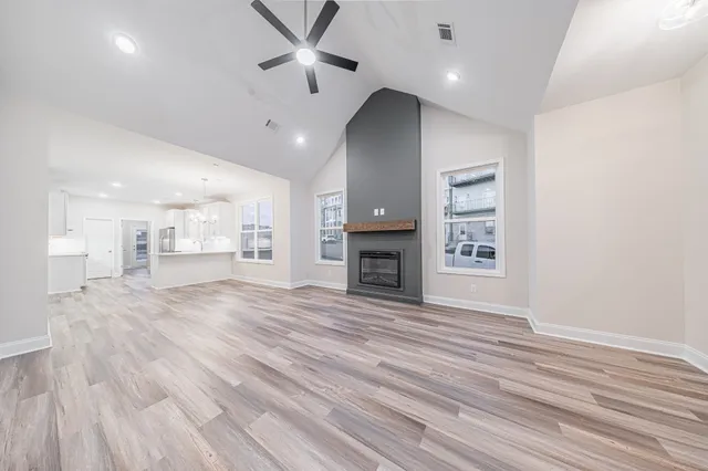 an empty room with wooden floor fireplace and windows