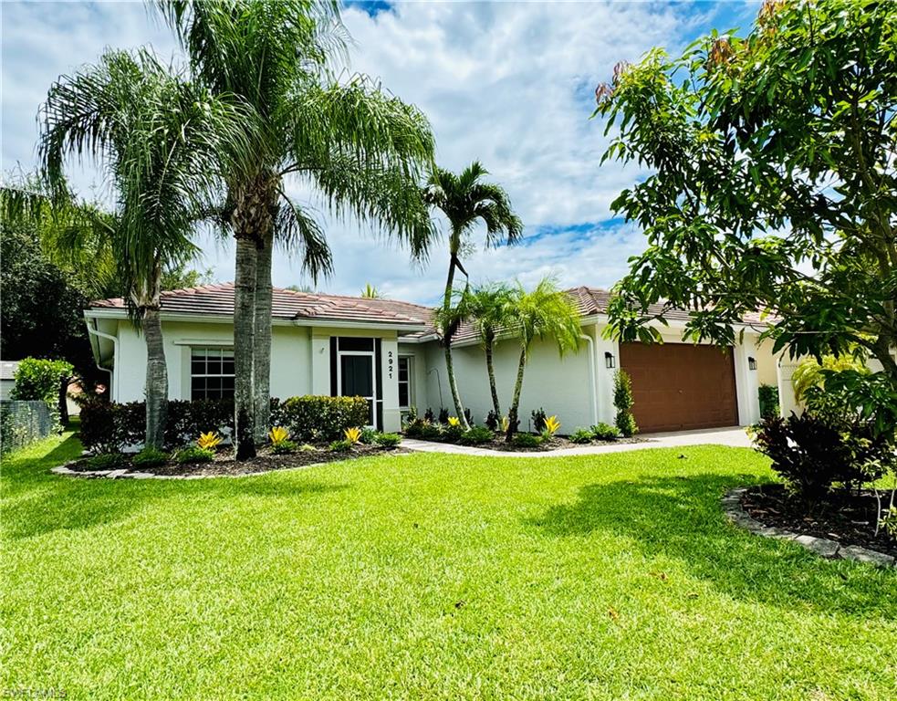 2921 Inlet Cove Lane East Naples, FL 34120 - Photo 1 of 48 a front view of a house with a yard and palm trees