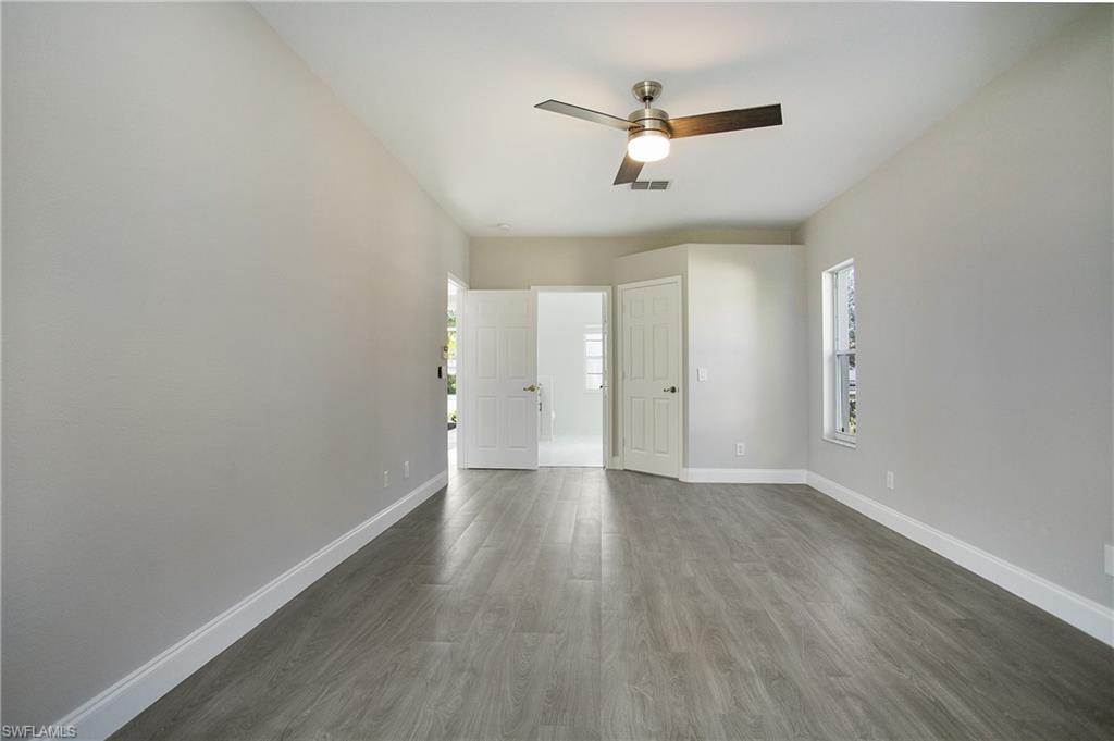 2921 Inlet Cove Lane East Naples, FL 34120 - Photo 18 of 48 an empty room with wooden floor ceiling fan and windows