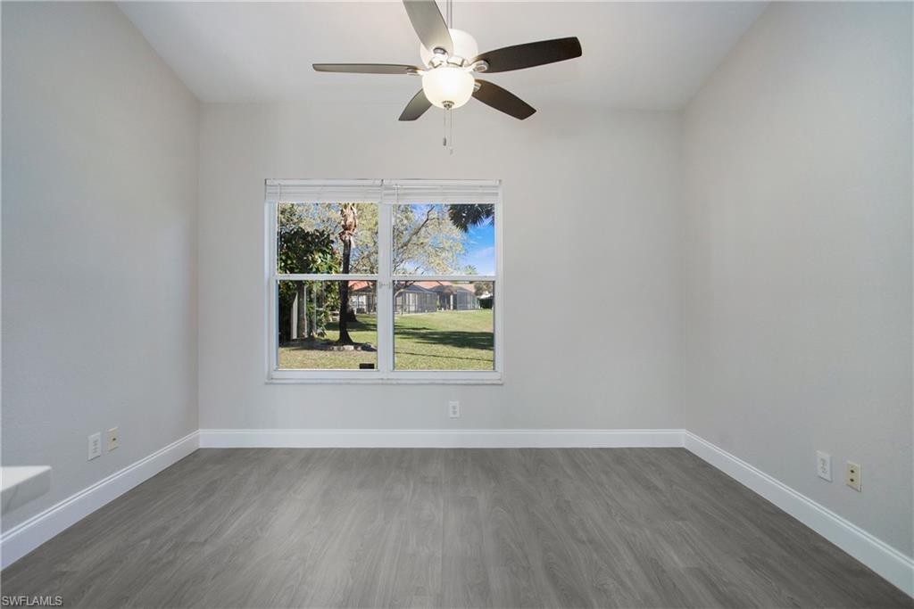 2921 Inlet Cove Lane East Naples, FL 34120 - Photo 25 of 48 an empty room with wooden floor chandelier fan and windows