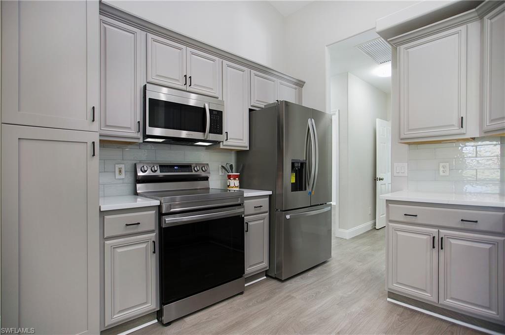 2921 Inlet Cove Lane East Naples, FL 34120 - Photo 7 of 48 a kitchen with stainless steel appliances white cabinets white and a refrigerator