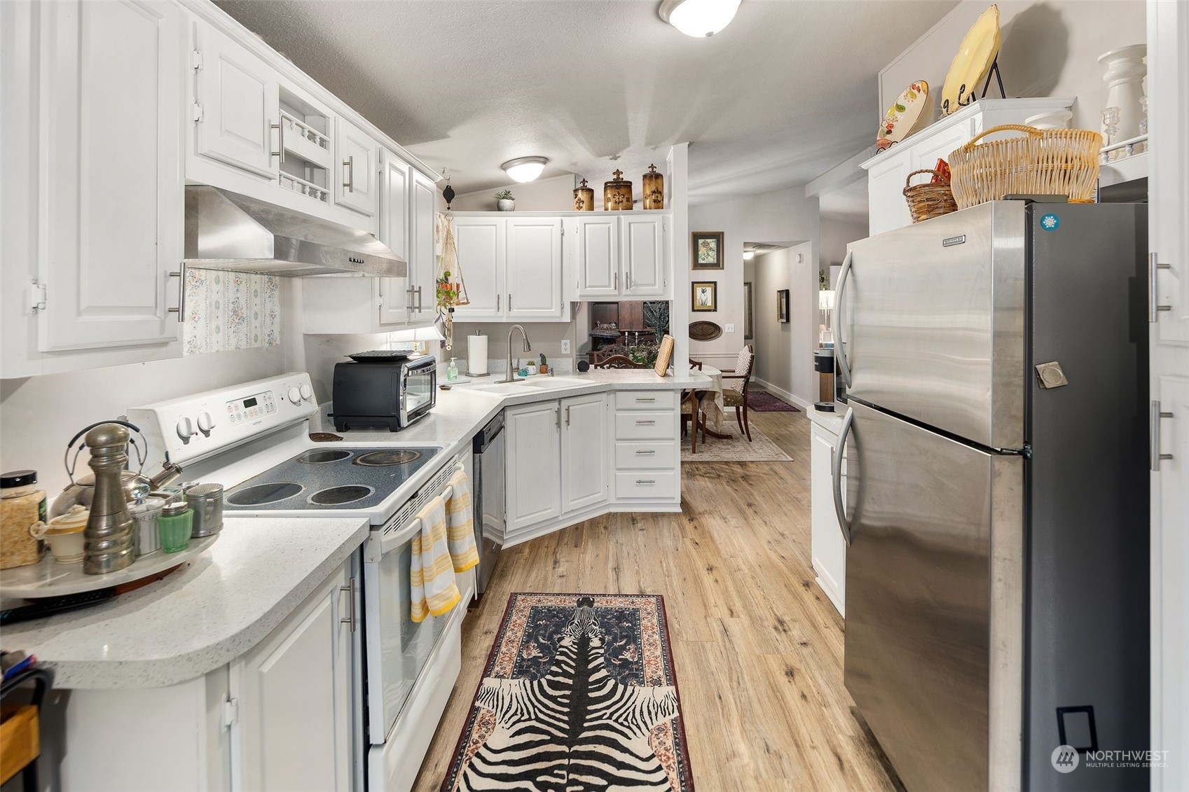 8730 206th Street Southeast, Unit 24 Snohomish, WA 98296 - Photo 11 of 33 a kitchen with stainless steel appliances granite countertop a refrigerator a stove and a sink with wooden floor
