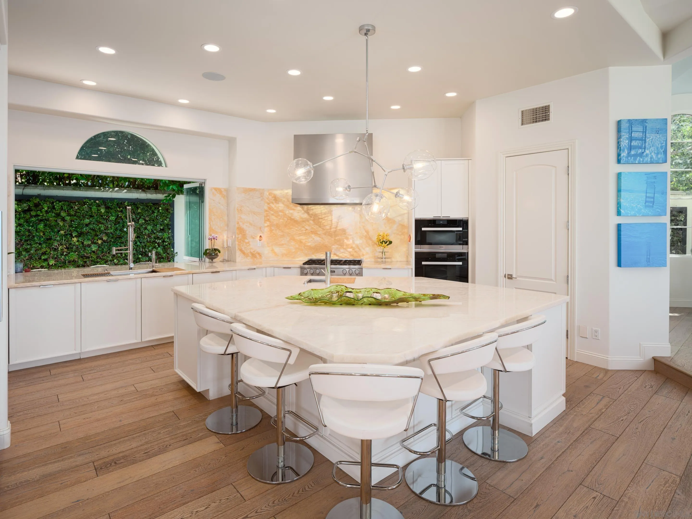 7403 Hillside Drive La Jolla, CA 92037 - Photo 29 of 52 a kitchen with stainless steel appliances kitchen island granite countertop a stove a refrigerator and a dining table with wooden floors