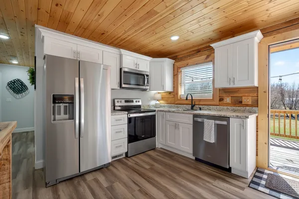 a kitchen with stainless steel appliances granite countertop a refrigerator a stove a sink and a microwave