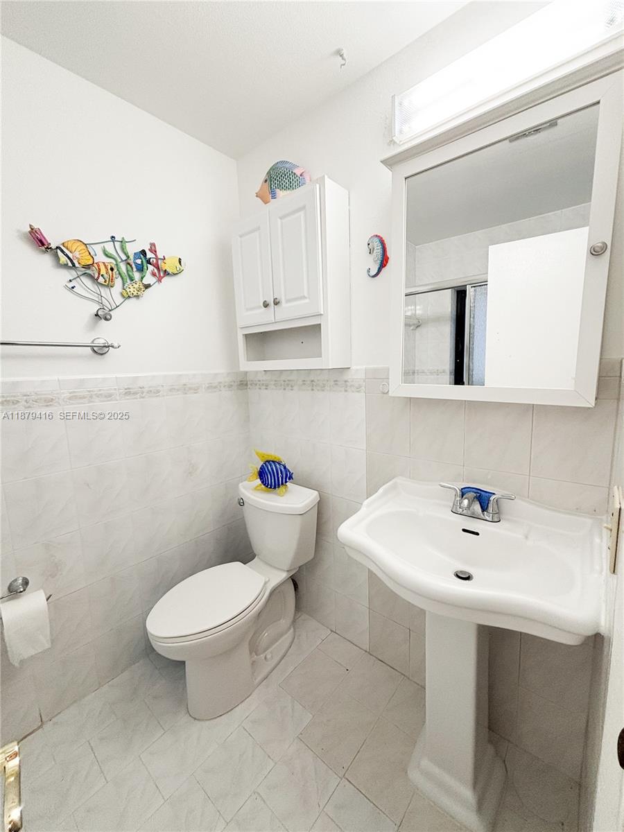 6865 Northwest 169th Street, Unit D Hialeah, FL 33015 - Photo 14 of 21 a bathroom with a sink a toilet and a mirror