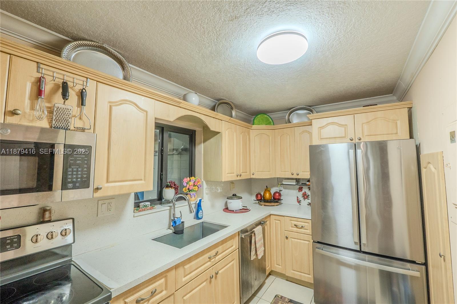 6865 Northwest 169th Street, Unit D Hialeah, FL 33015 - Photo 8 of 21 a kitchen with stainless steel appliances a refrigerator sink and white cabinets
