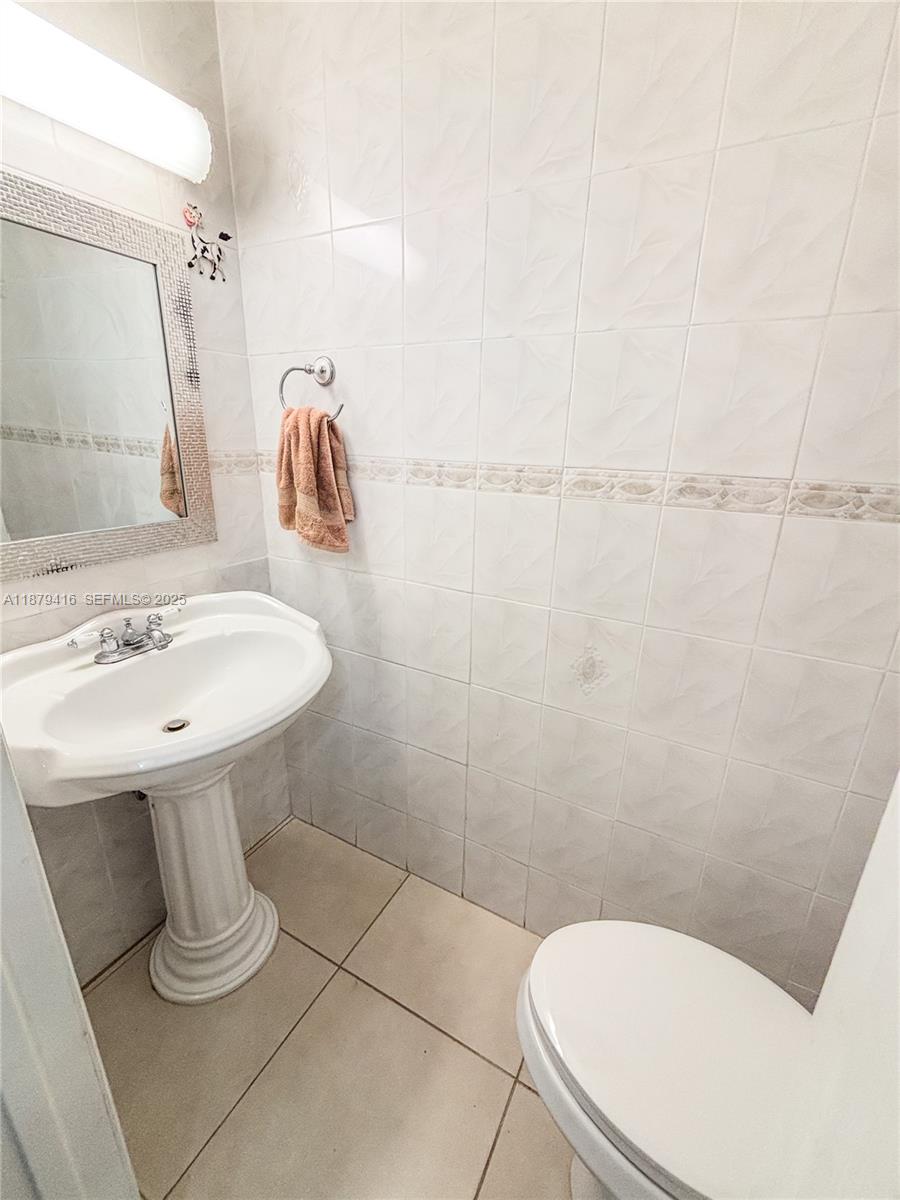 6865 Northwest 169th Street, Unit D Hialeah, FL 33015 - Photo 9 of 21 a bathroom with a sink a toilet and a mirror