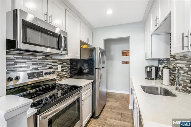 a kitchen with a sink stainless steel appliances a refrigerator and a stove
