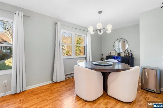 a dining room with wooden floor a chandelier a wooden table and chairs