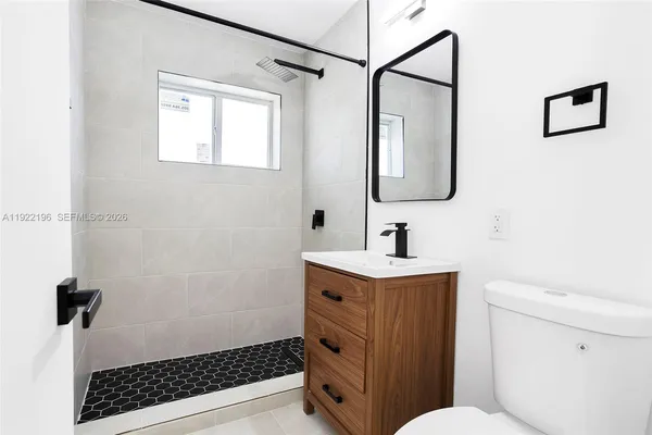 a bathroom with a sink a toilet a mirror and shower