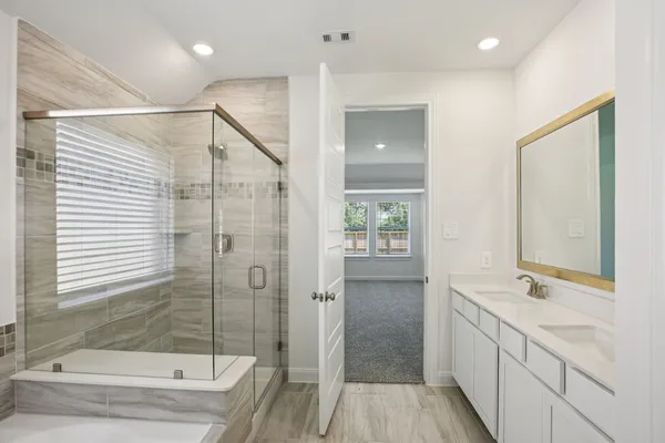 a bathroom with a double vanity sink and mirror with bathtub