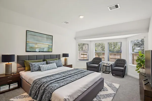 a bedroom with bed couch and large windows