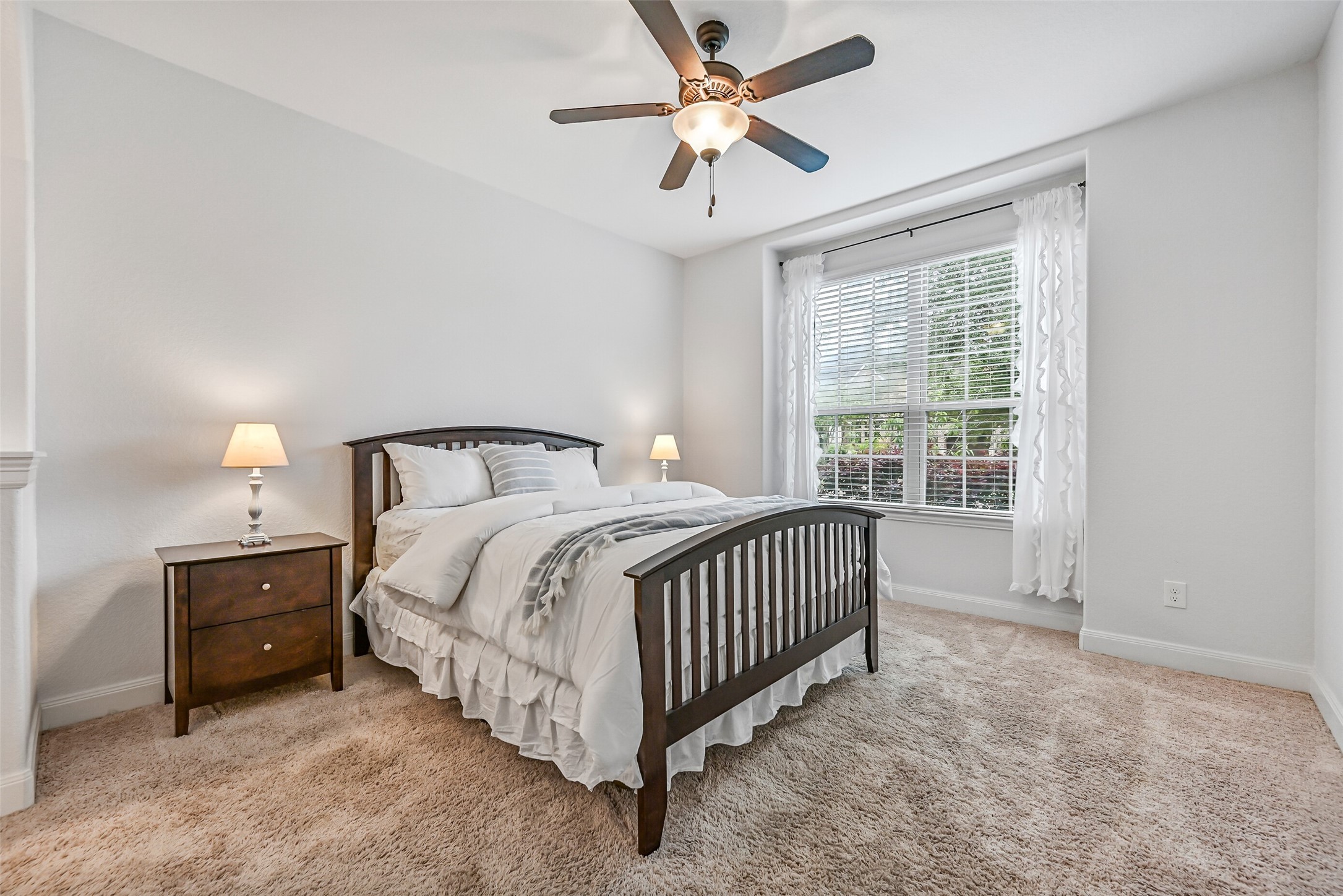1008 Point Isabel Lane Friendswood, TX 77546 - Photo 24 of 50 Continue into a first floor guest bedroom with soft carpet, neutral tones, a large front facing window for natural light, and an en suite bath. The private location makes it ideal for guests or multigenerational living.