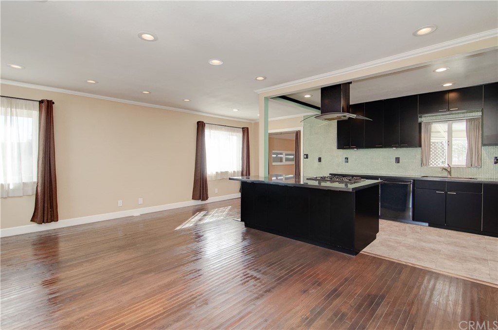 a living room with stainless steel appliances kitchen island granite countertop a sink wooden floor and view living room