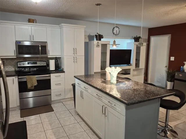 a kitchen with stainless steel appliances granite countertop a stove refrigerator and microwave