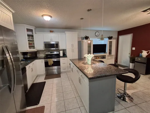 a kitchen with stainless steel appliances granite countertop a sink refrigerator and microwave