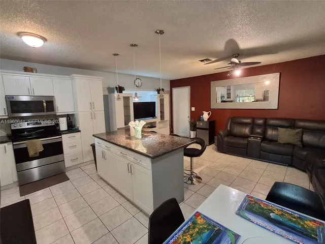 a kitchen with granite countertop a stove and white cabinets