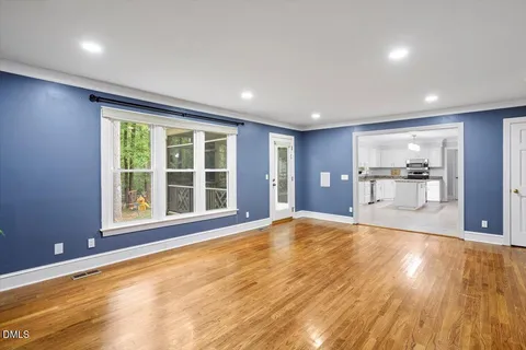 a view of an empty room with a window and wooden floor