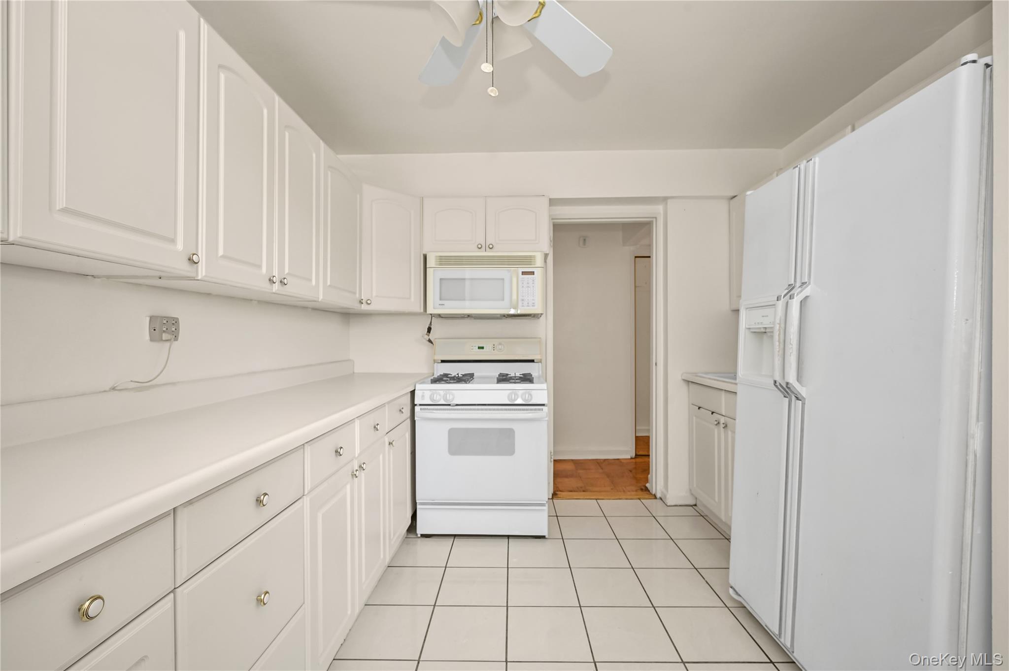 99-10 60th Avenue, Unit 1E Queens, NY 11368 - Photo 11 of 18 a kitchen with white cabinets and white appliances