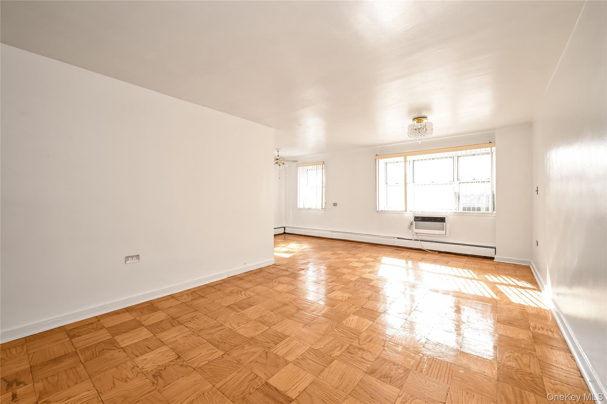 99-10 60th Avenue, Unit 1E Queens, NY 11368 - Photo 7 of 18 an empty room with wooden floor and windows