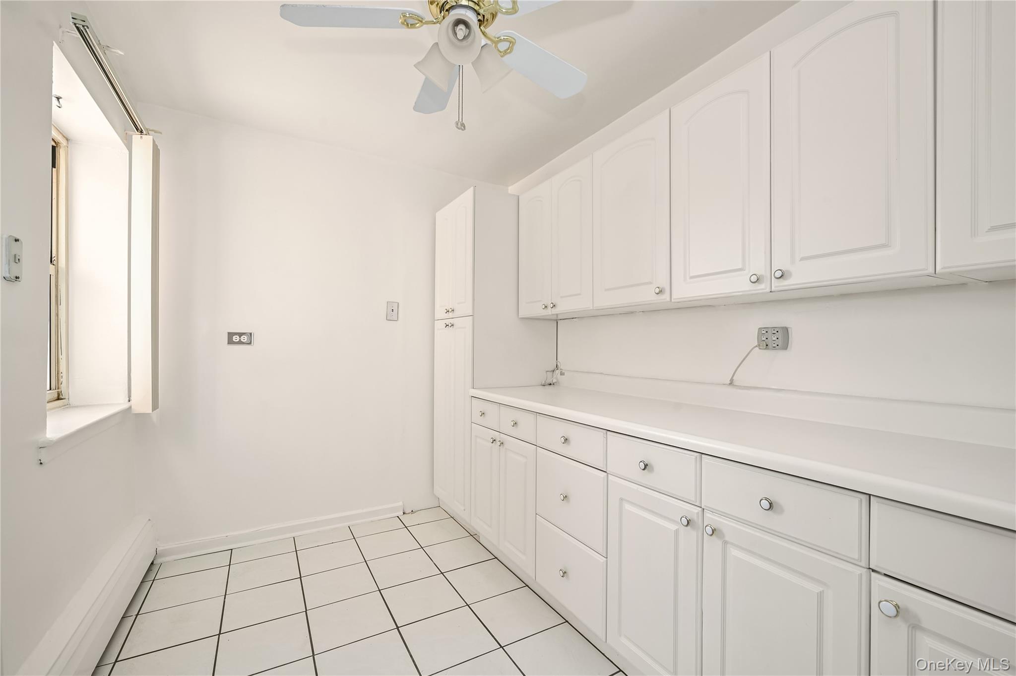 99-10 60th Avenue, Unit 1E Queens, NY 11368 - Photo 10 of 18 a kitchen with white cabinets and window