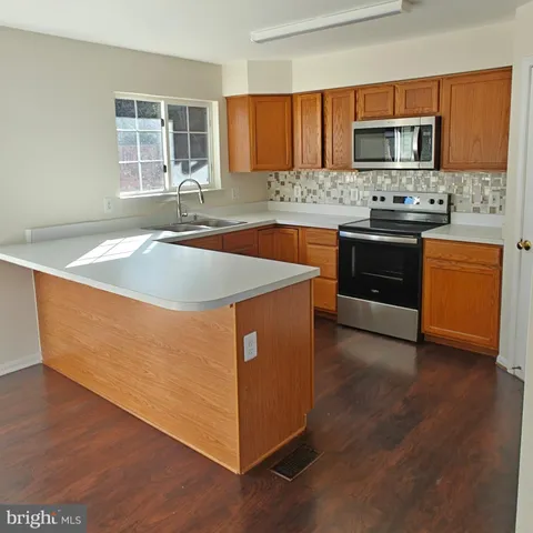 a view of an empty room with wooden floor and closet