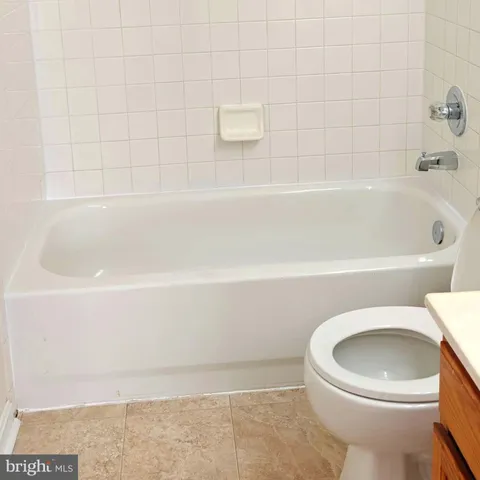 a view of a hallway with wooden floor and a bathroom