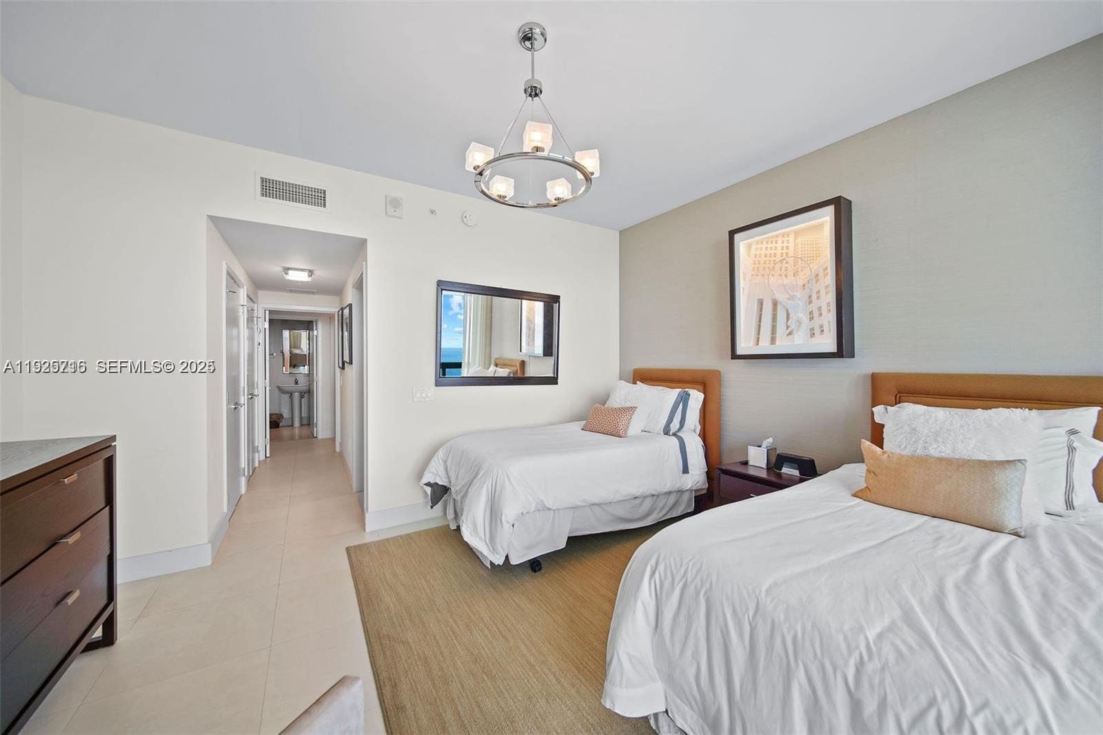 6899 Collins Avenue, Unit 1801 Miami Beach, FL 33141 - Photo 28 of 67 a bedroom with two beds and a chandelier