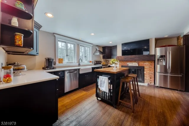 a kitchen with stainless steel appliances granite countertop a refrigerator a sink dishwasher a stove and a dining table with wooden floor