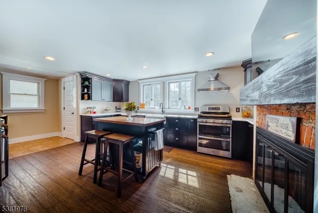 a kitchen with stainless steel appliances kitchen island granite countertop a stove a refrigerator a sink a dining table and chairs with wooden floor