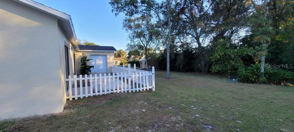 12200 Norvell Road Spring Hill, FL 34609 - Photo 15 of 16 a view of a yard with large trees plants and wooden fence