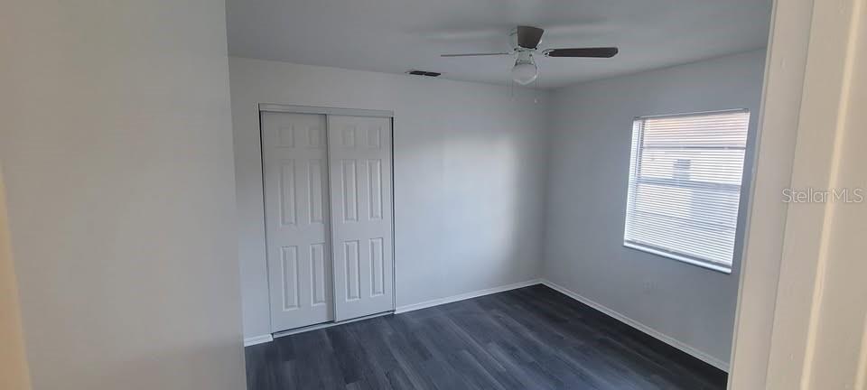 12200 Norvell Road Spring Hill, FL 34609 - Photo 10 of 16 an empty room with wooden floor ceiling fan and windows