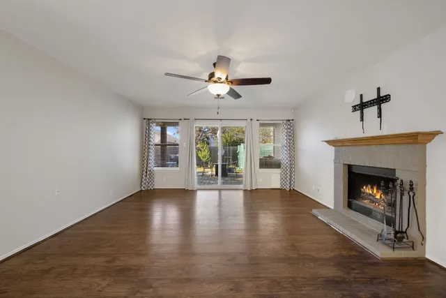 a view of an empty room with wooden floor fireplace and a window