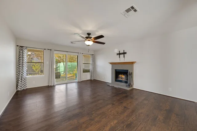 a view of an empty room with wooden floor fireplace and a window