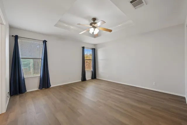 an empty room with wooden floor ceiling fan and window