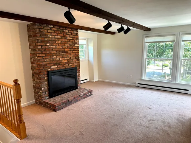 an empty room with windows and fireplace